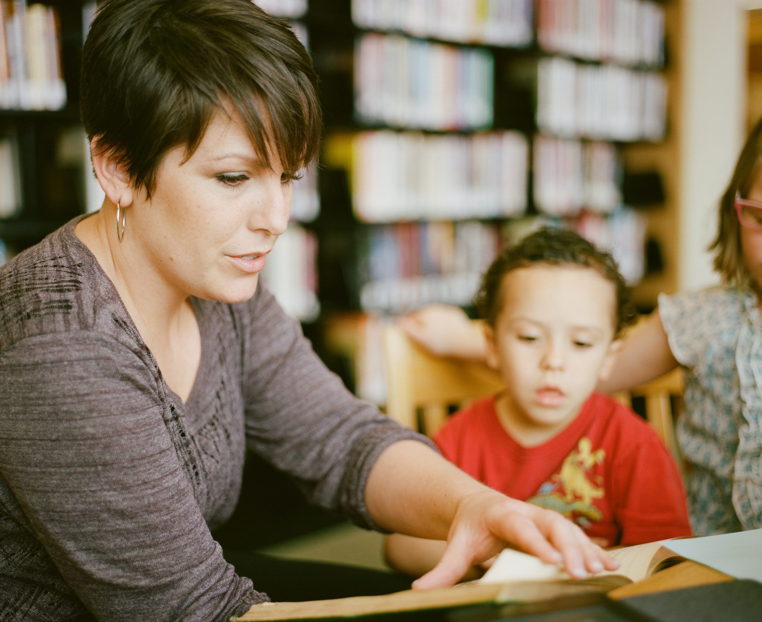 A therapist reading with a young boy in a library